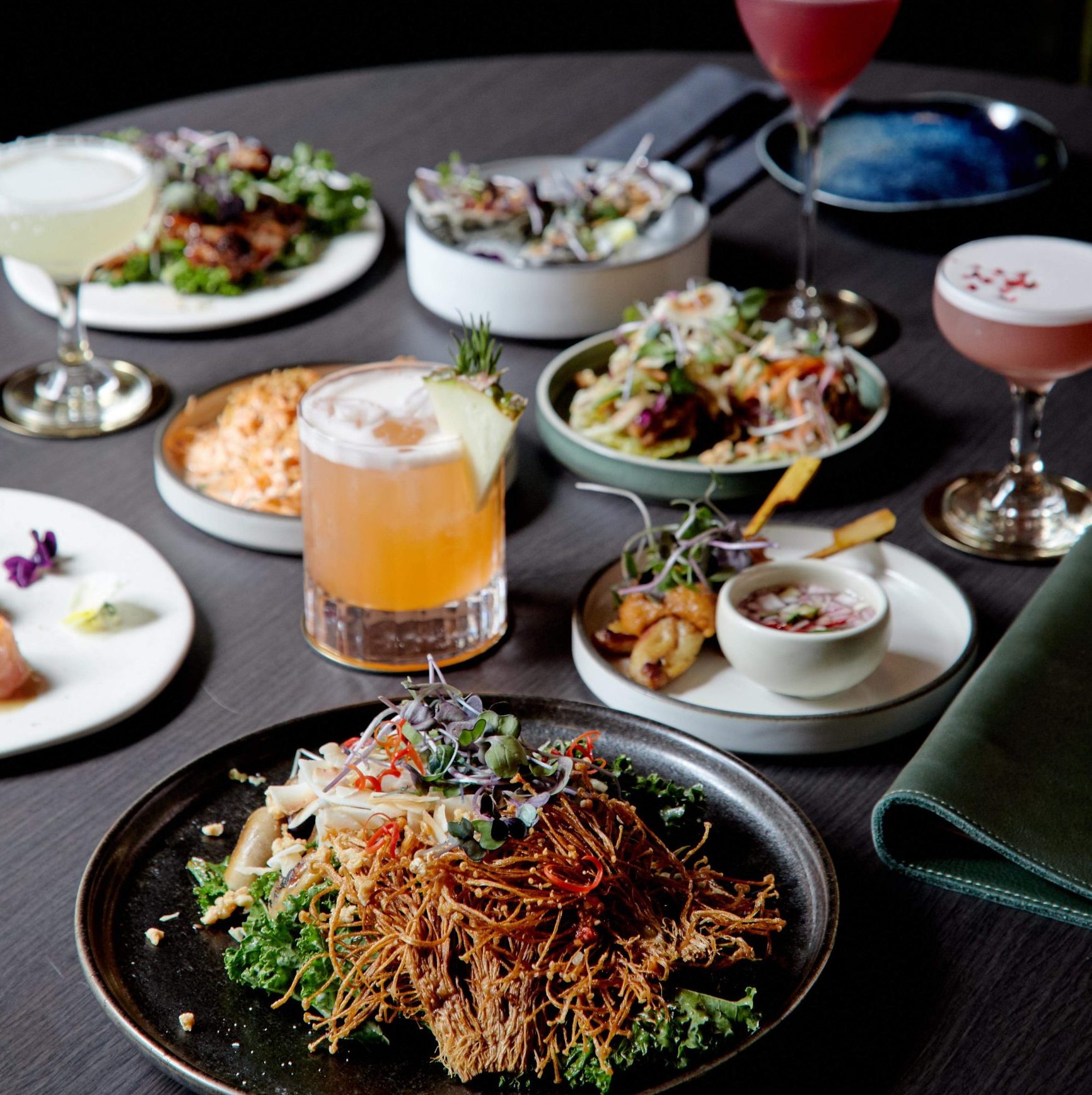 A table covered with Asian fusion share plates and cocktails at Kiss and Tell in Melbourne