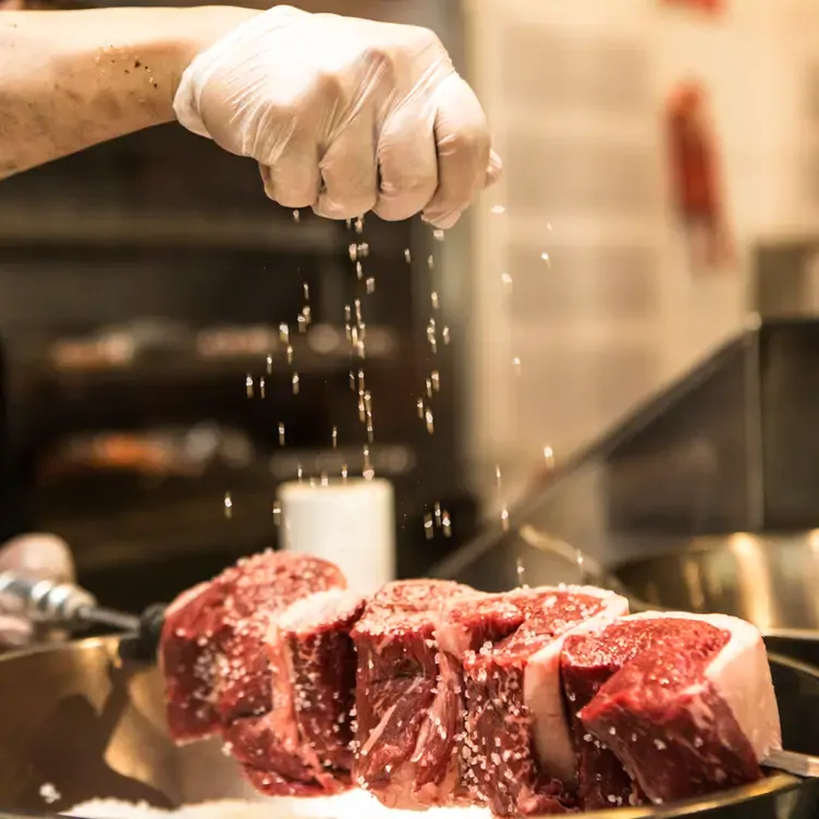 A chef seasons a meat skewer on a grill at Braza Churrascaria in Sydney