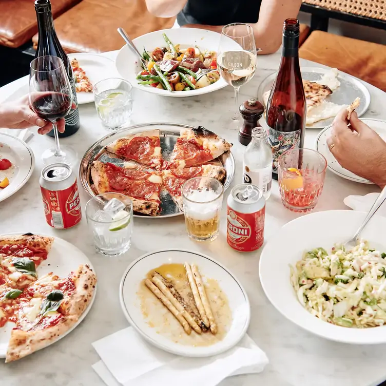 A spread of Italian dishes and drinks including pizza, pasta, wine and beers at Gilson, one of the best outdoor restaurants in Melbourne