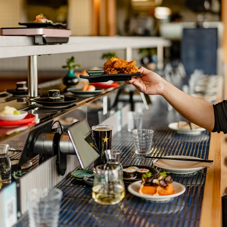 A diner lifts a dish off the sushi train at Chocolate Buddha.