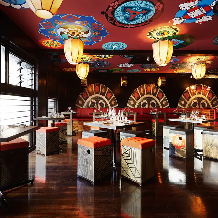 An interior space at Ichi Ni Nana with red-cushioned stools and patterns on the walls and ceiling.