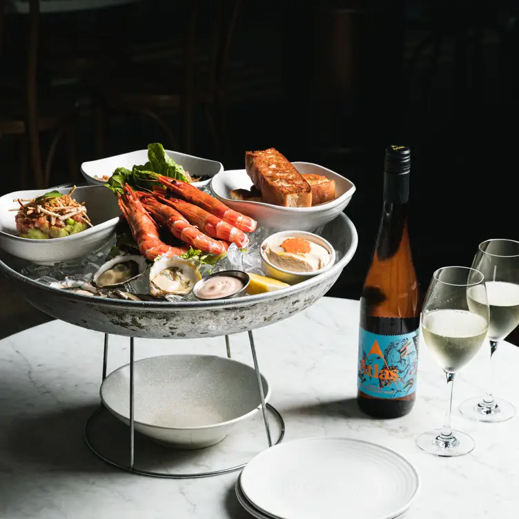 A seafood platter sits next to a bottle of wine and two wine glasses at love.fish in Sydney