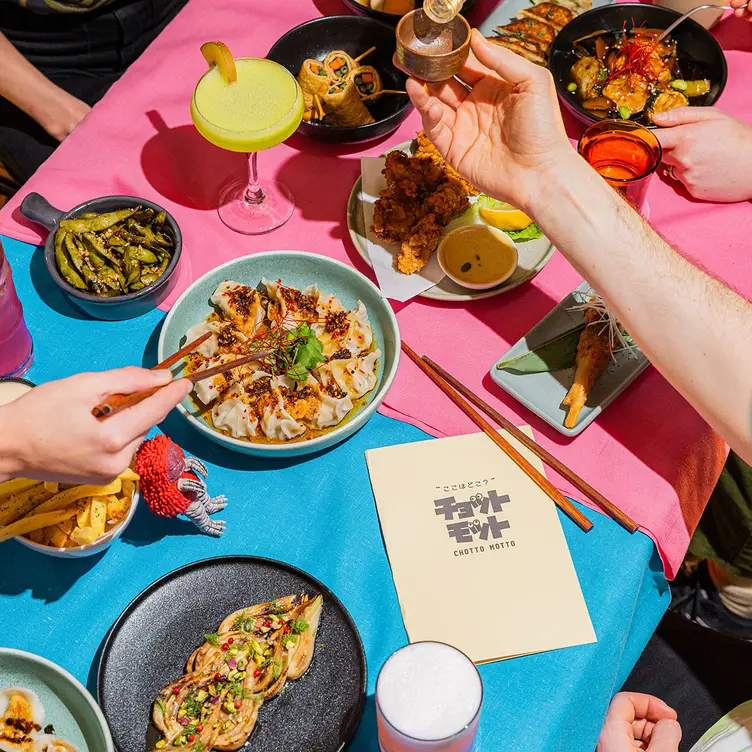 A table laid with multiple dishes and drinks and Chotto Motto.