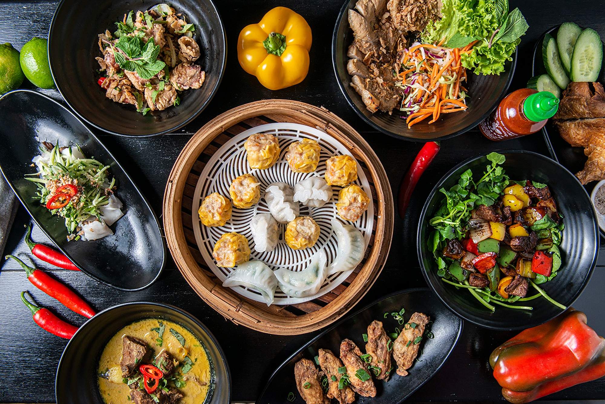 An array of Vietnamese-style dishes with dumplings, buddha bowls and salads on a dark table at a restaurant.