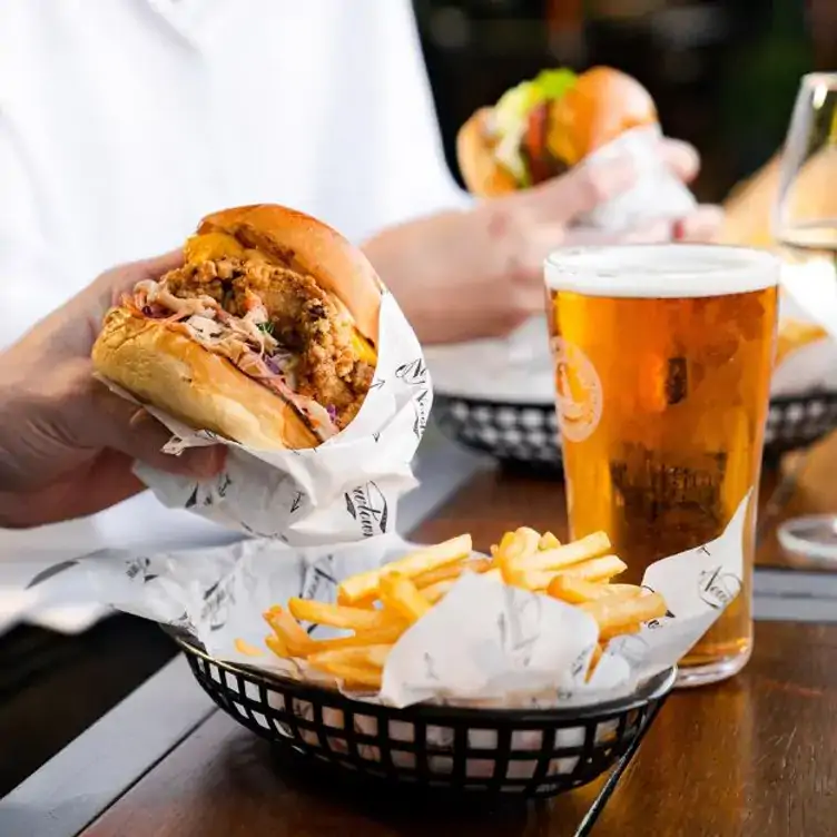 A diner eats a burger with a side of fries and a pint of beer at Newtown Hotel in Sydney