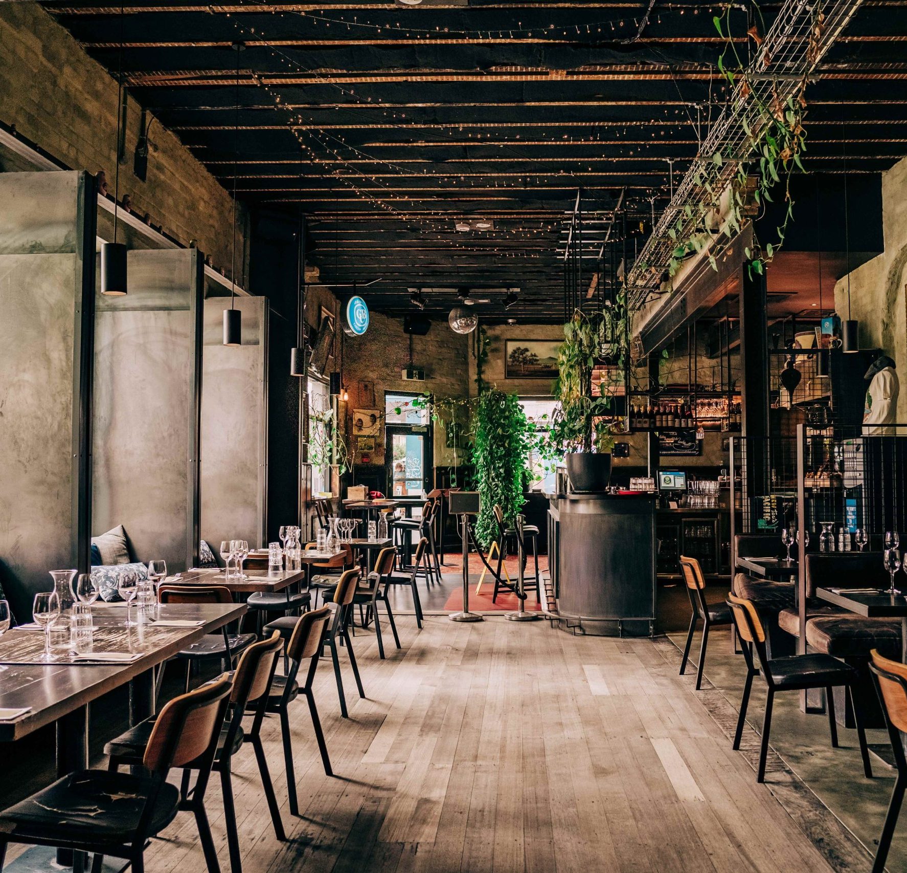 A pub's interiors with wooden floors, tables, chairs and string lights on the ceiling