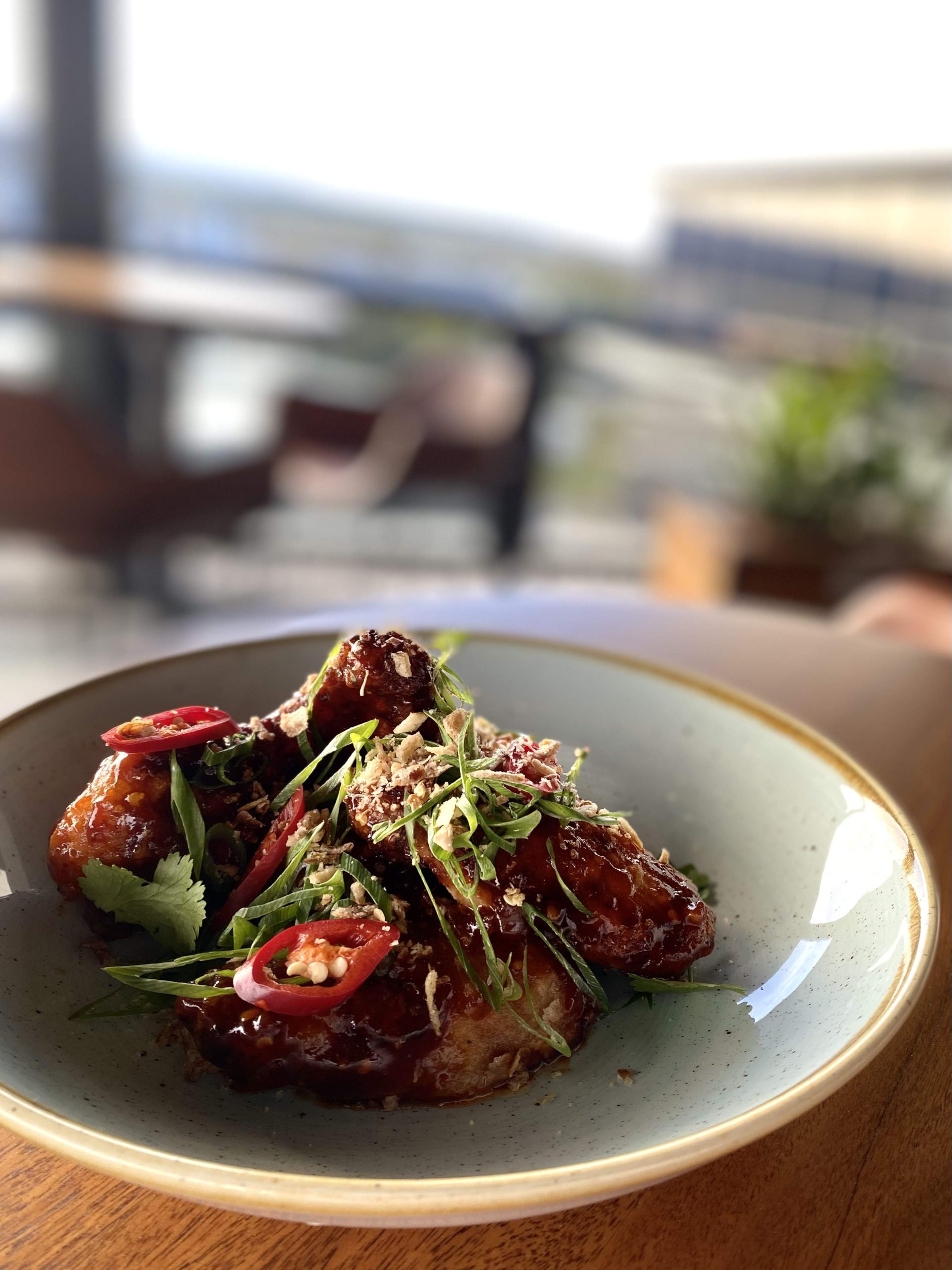 A cream bowl with sticky, chilli chicken wings