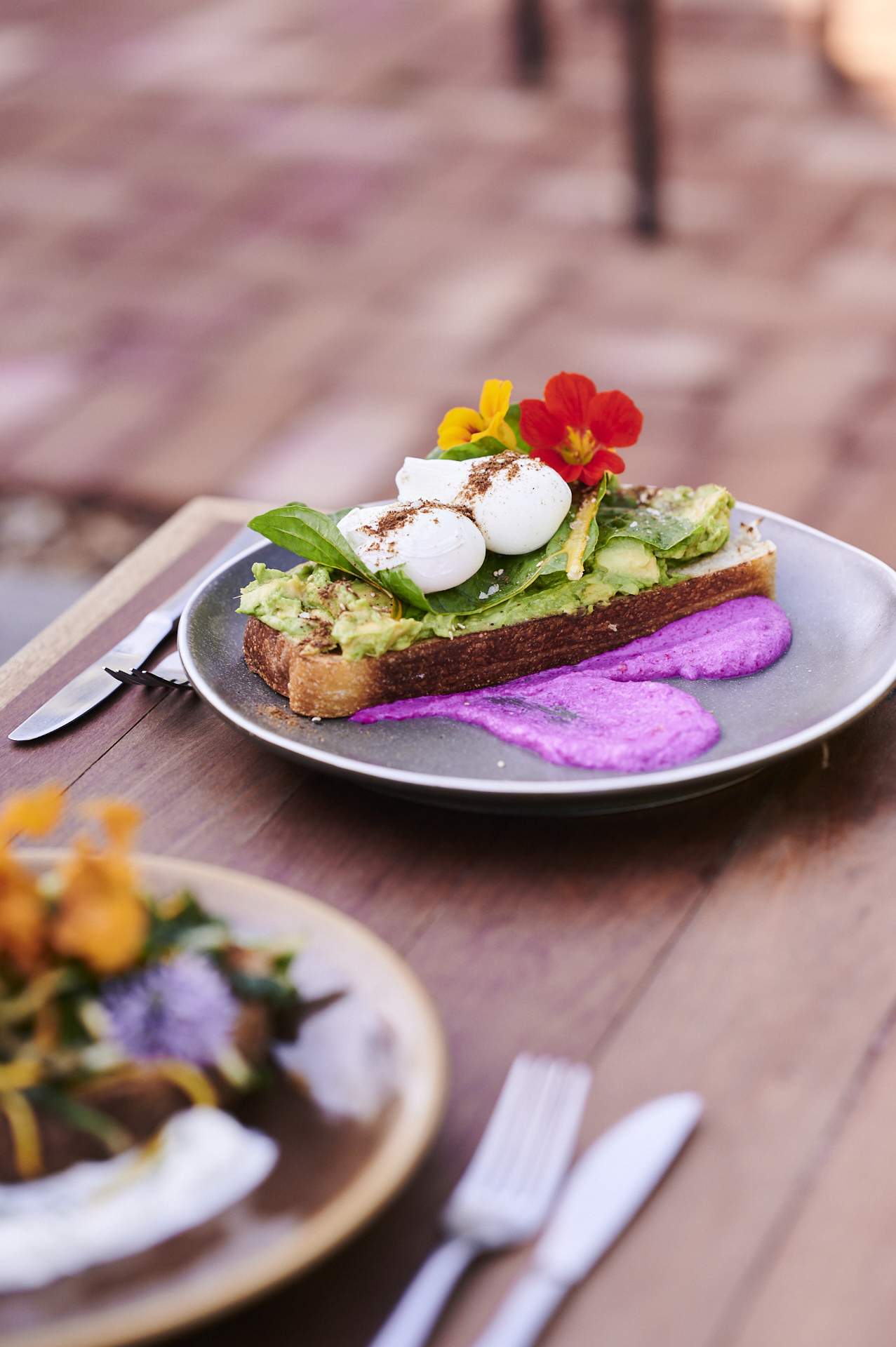 Avocado on toast with poached eggs and edible flowers