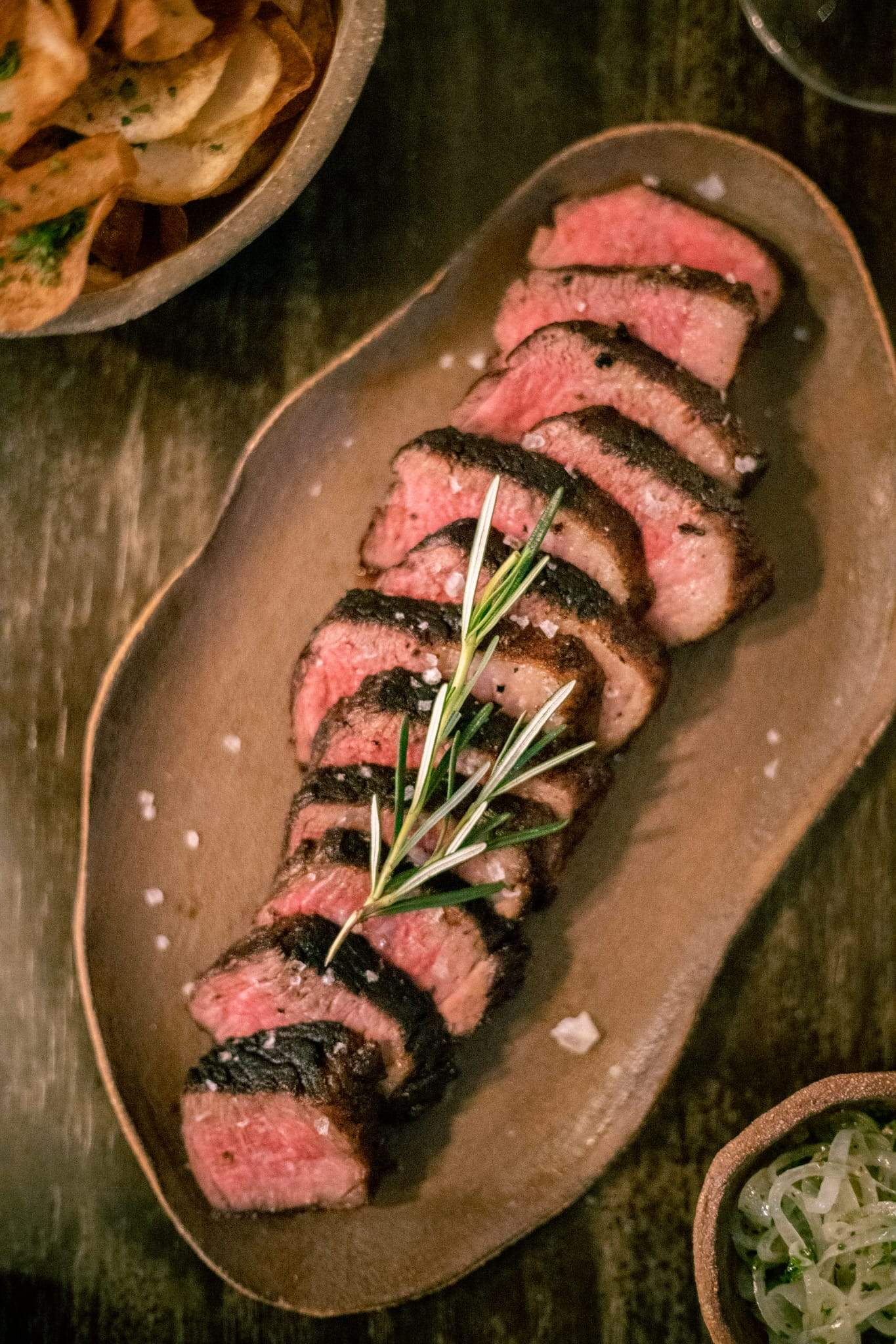 A wooden table with a shared plate of beef picanha.