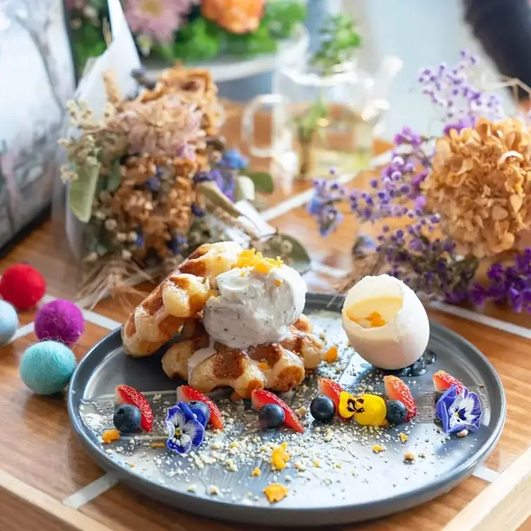 Two waffles topped with ice cream and adorned with flowers at Cafe 0.6, one of the best brunch places in Sydney