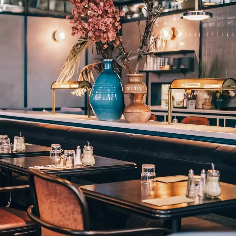 Elegant interiors with tables, chairs, flower vases and a marble bar at Lobby Boy, a restaurant in Sydney