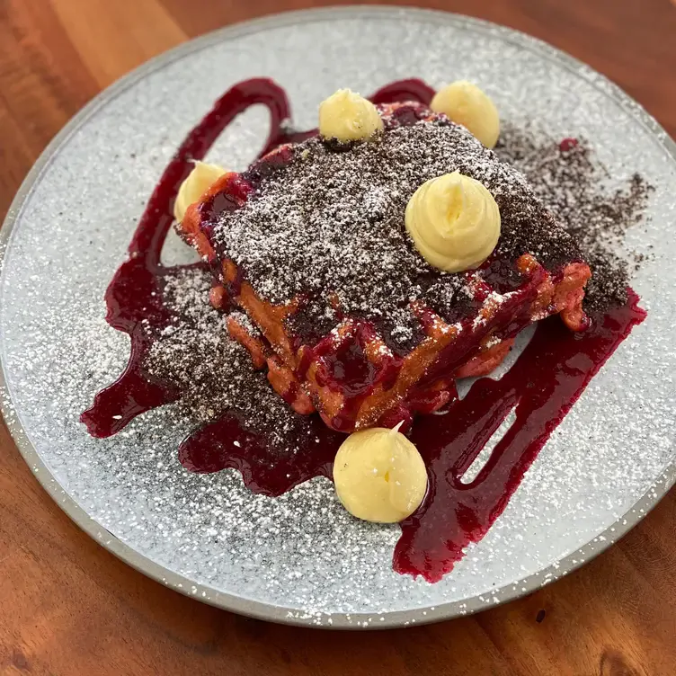 Waffles covered in berry sauce and topped with cream and icing sugar at The Feasting Shed @The Garden Feast, one of the best brunch in Melbourne