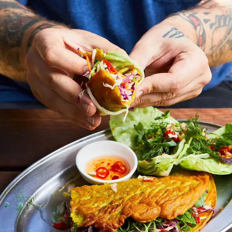 A diner holds an omelette roll at Jardin Tan, a restaurant in Melbourne