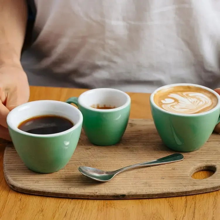 Three cups of coffees sit on a wooden tray at Vertue Coffee Roasters, a restaurant in Melbourne