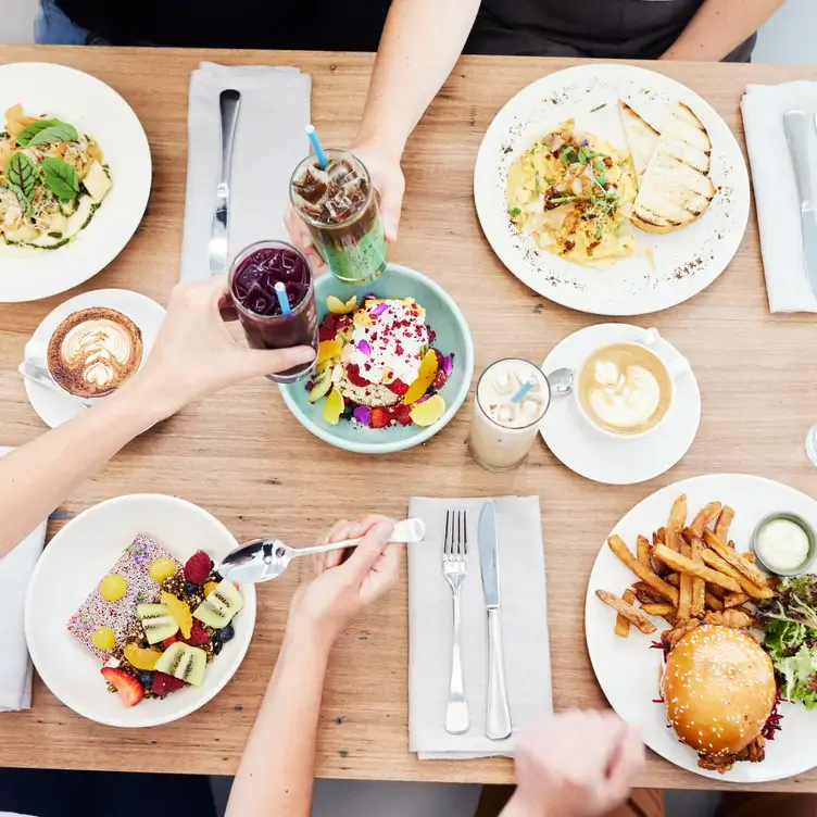 Two diners cheer over a table of dishes at Industry Beans, a restaurant in Melbourne