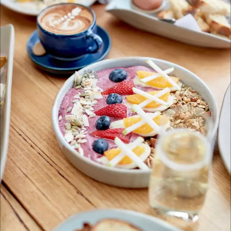 A fruit bowl sits next to a coffee at Nancy Eatery, one of the best brunch spot in Melbourne