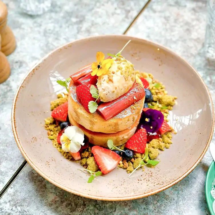 A bowl of pancakes topped with fruits and flowers at Flower Child Cafe in Sydney