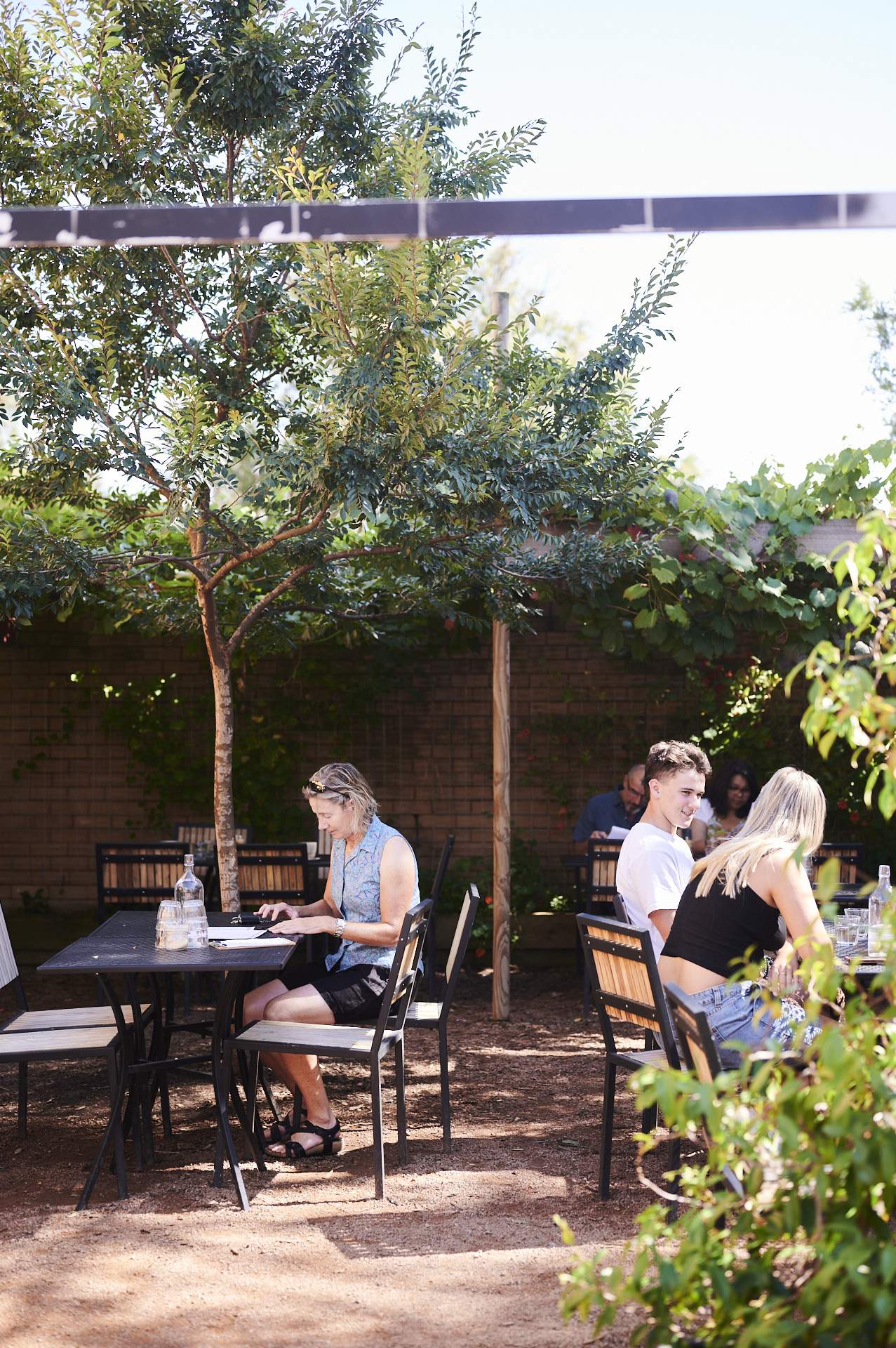 Customers sitting in an outdoor courtyard at Canberra cafe Two Before Ten’s Aranda campus.