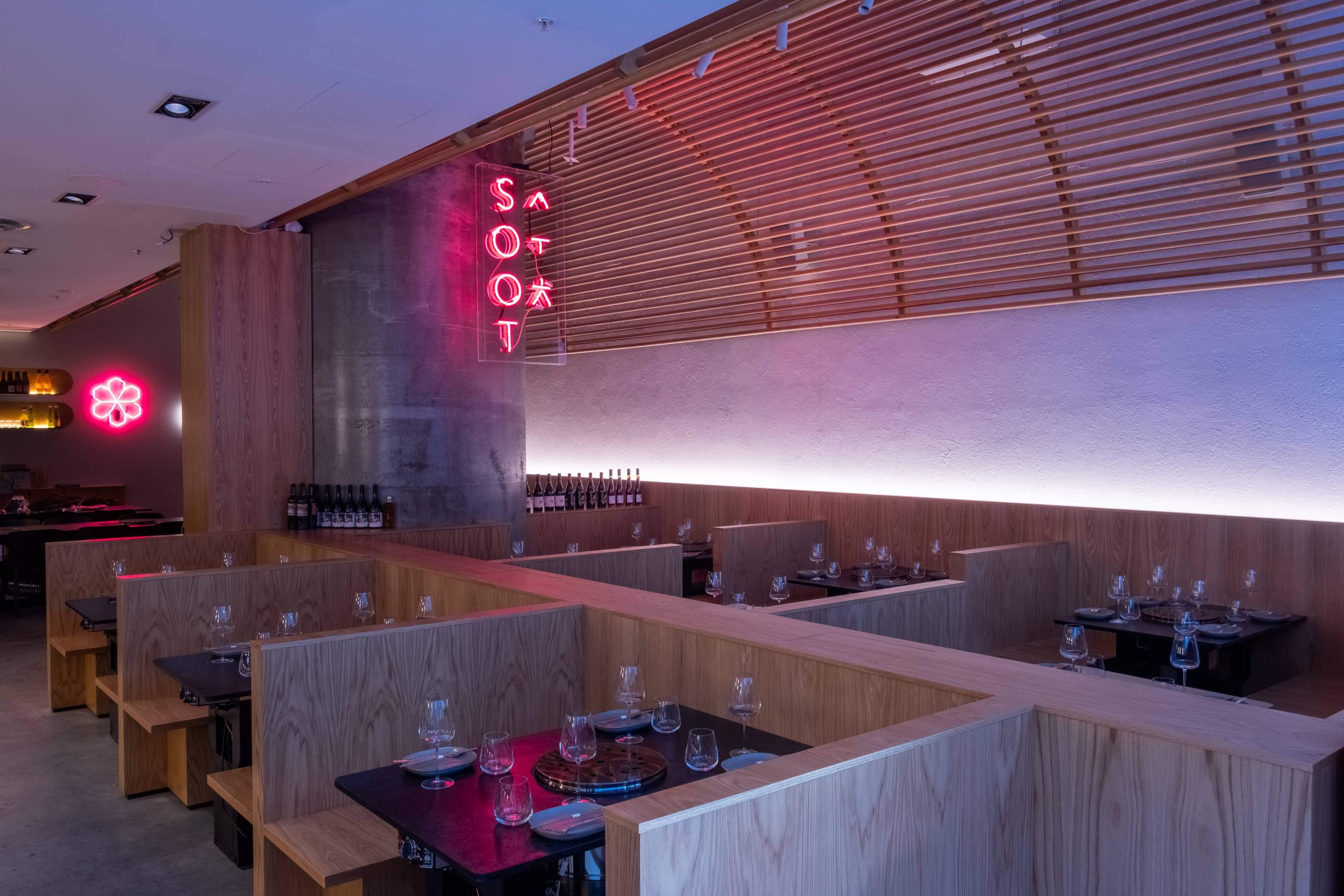 A dimly lit dining room with tightly packed wooden booths at Soot in Sydney