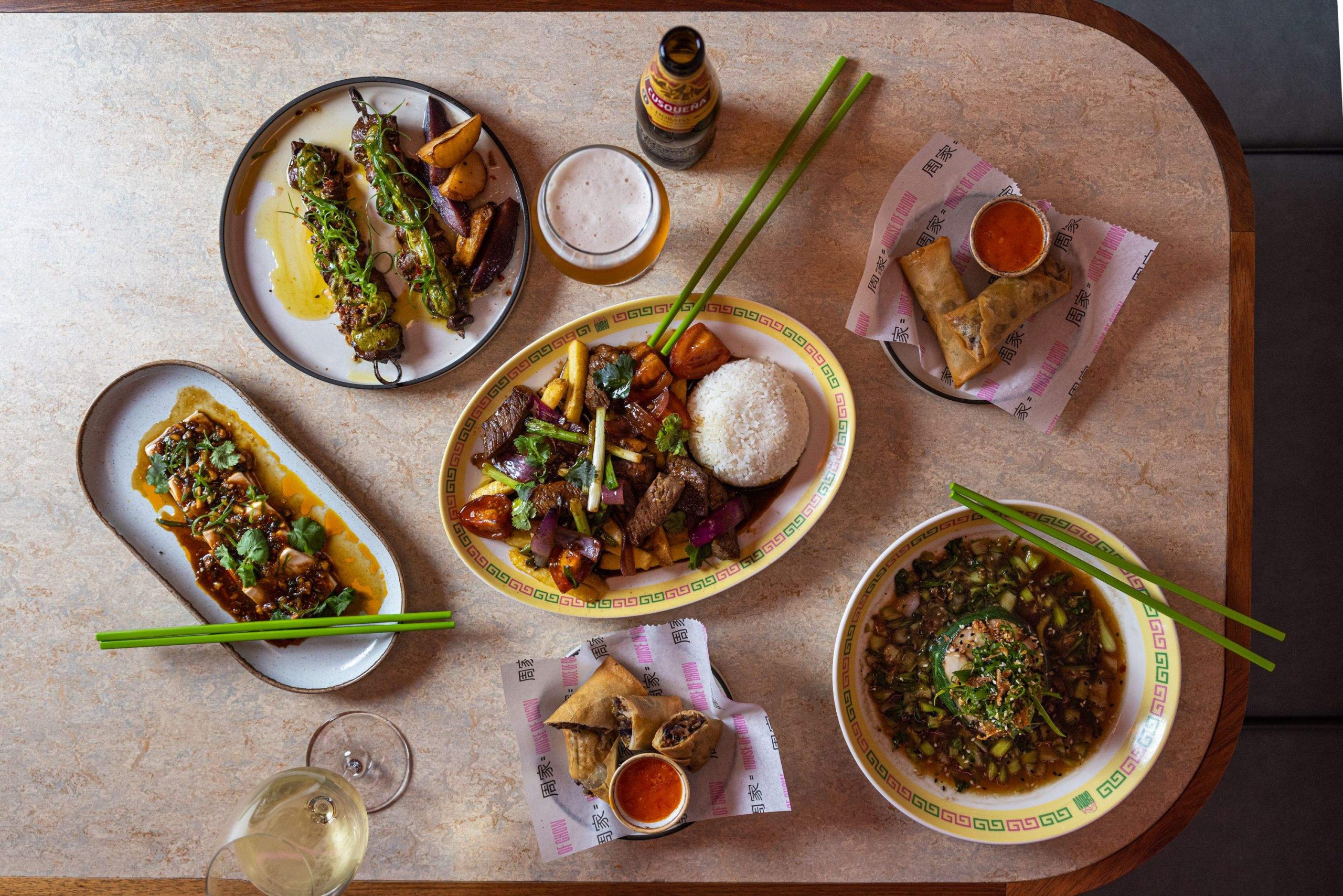 A table with a selection of Chifa dishes including dan dan noodles, empanadas, spring rolls, and beef skewers at Casa Chow in Brisbane