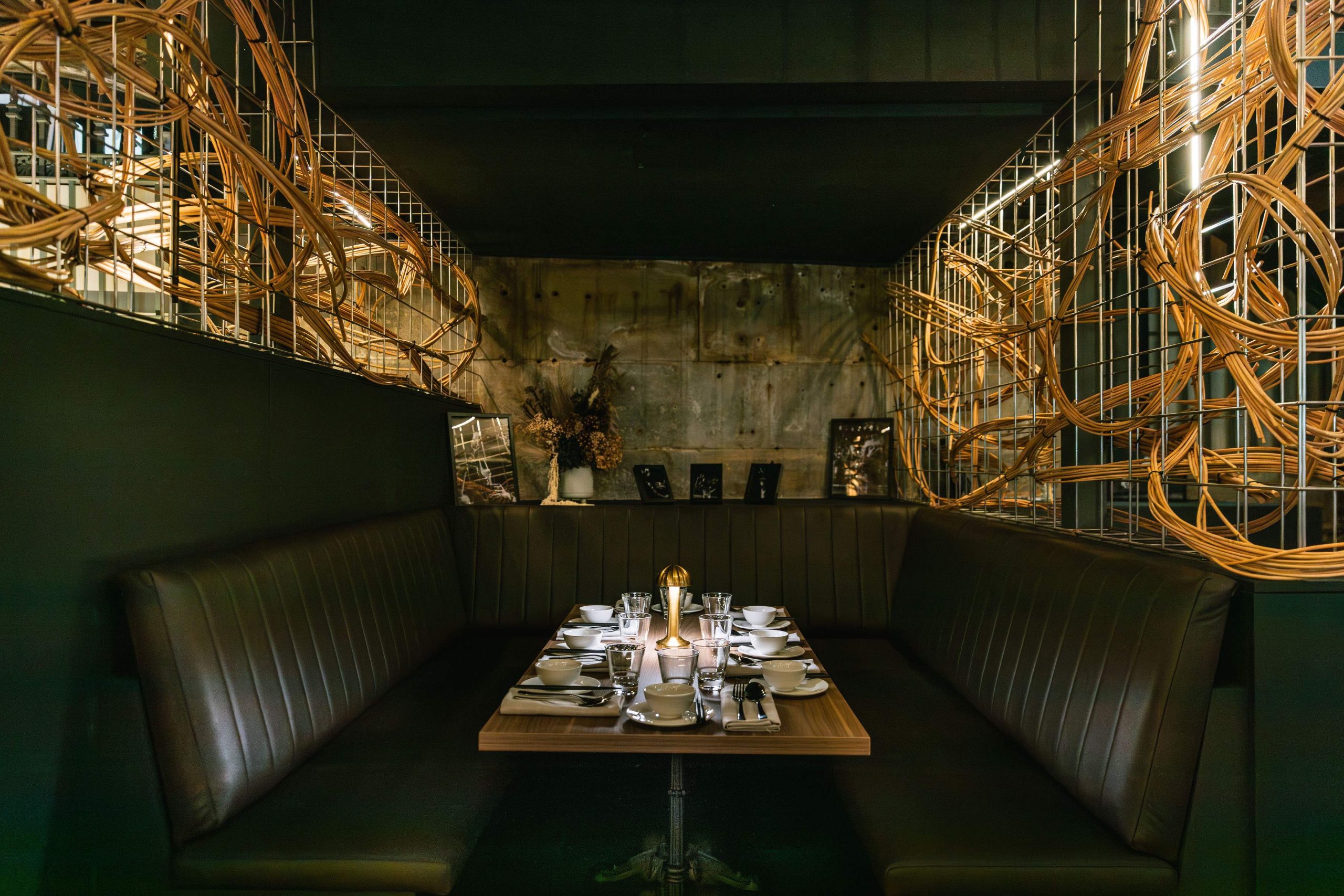 Black leather booth seating with a wooden table in the center at Sydney restaurant Hustlers.