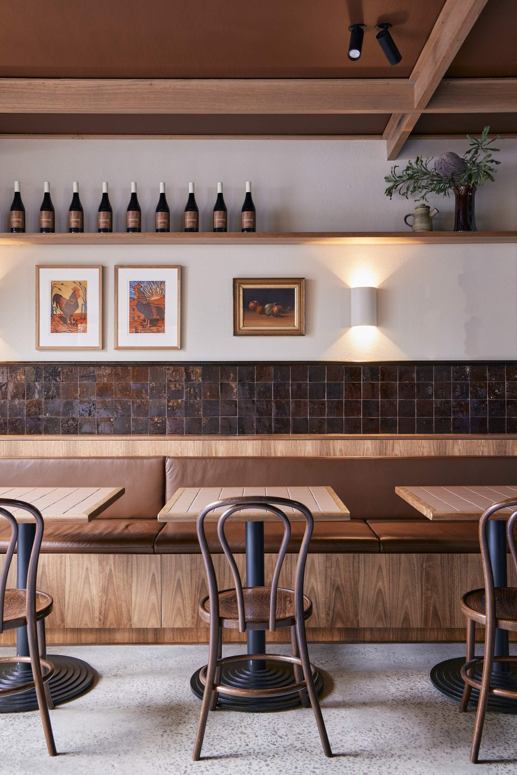 Sunlight hits the downstairs dining space adorned with spotted gum furnishings, leather booth seating, art deco tiles, and framed prints at The Courthouse Hotel in Melbourne.