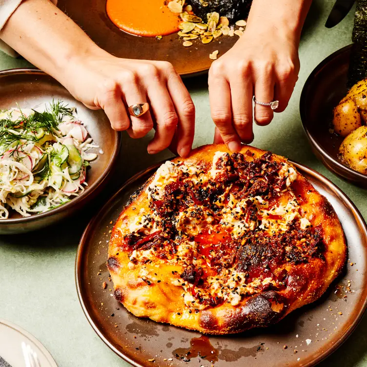 Two hands grab a slice of pizza at Lona Misa, , one of the best vegan restaurants in Melbourne