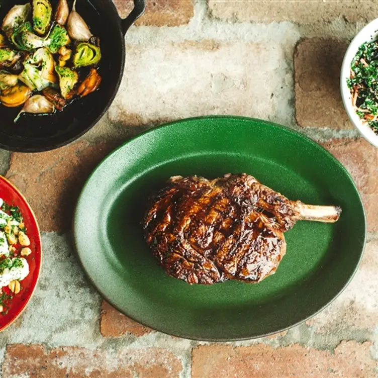 A grilled rib eye steak and other dishes resting on bricks at Butcher and the Farmer, one of the best steak restaurants in Sydney. Credit: Butcher and the Farmer