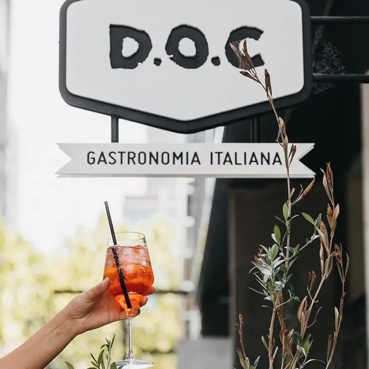 Someone toasts a drink to the sign outside DOC Pizza and Mozzarella Bar, one the best Italian restaurants in Melbourne. Credit: DOC Pizza & Mozzarella Bar