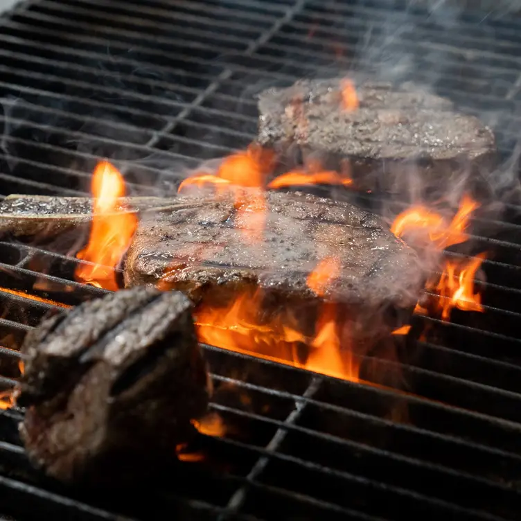 Steaks sizzling on the grill at Emerge, one of the best steak restaurants in Melbourne. Credit: Emerge