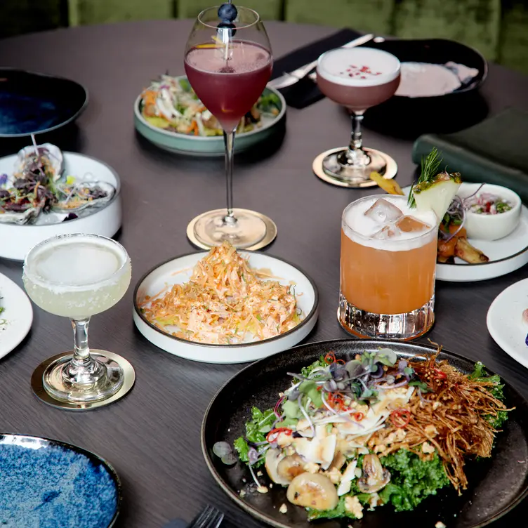 A table packed with cocktails and dishes at Kiss and Tell, one of the best Asian restaurants in Melbourne.