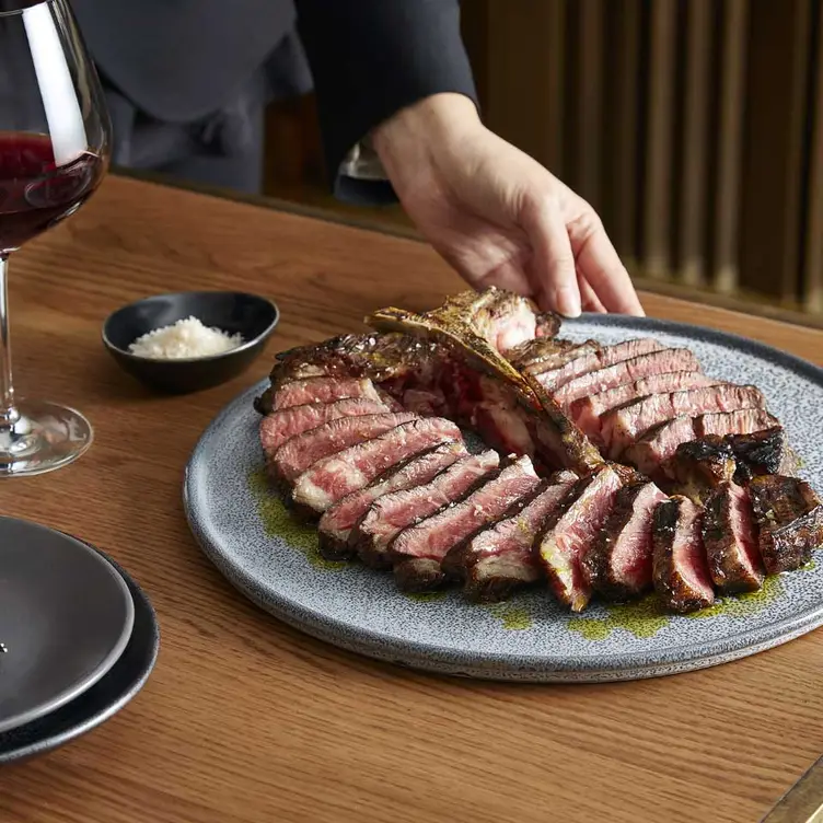 A sliced T-bone being presented at Mode Kitchen & Bar, one of the best steak restaurants in Sydney. Credit: Mode Kitchen & Bar