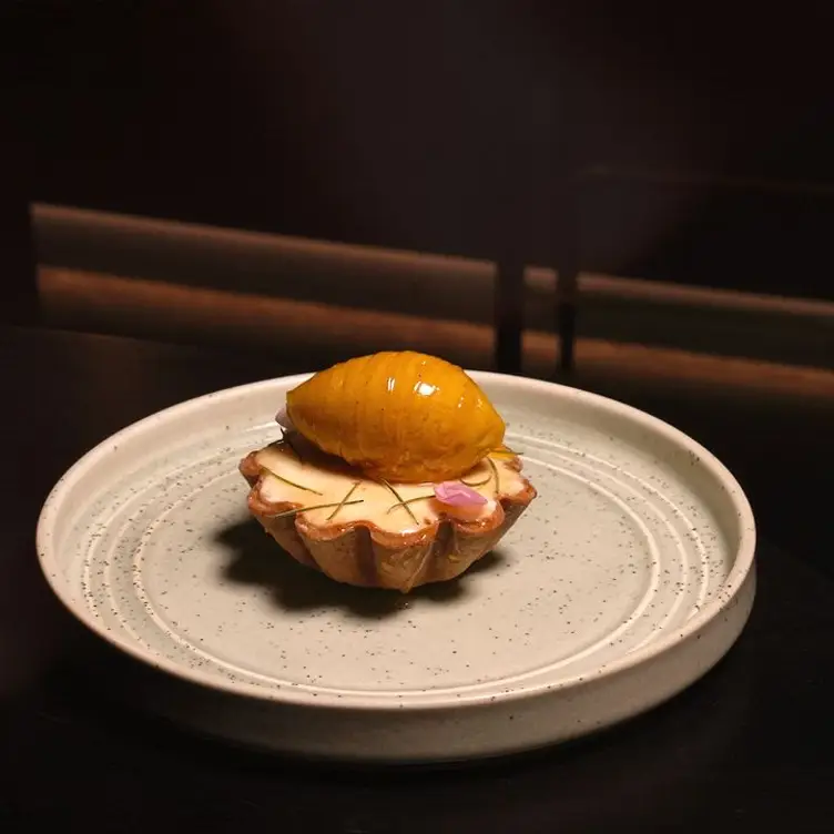 A dessert tart with a pale cream filling and a yellow scoop on top at Mr Vain, one of the best Asian restaurants in Brisbane.