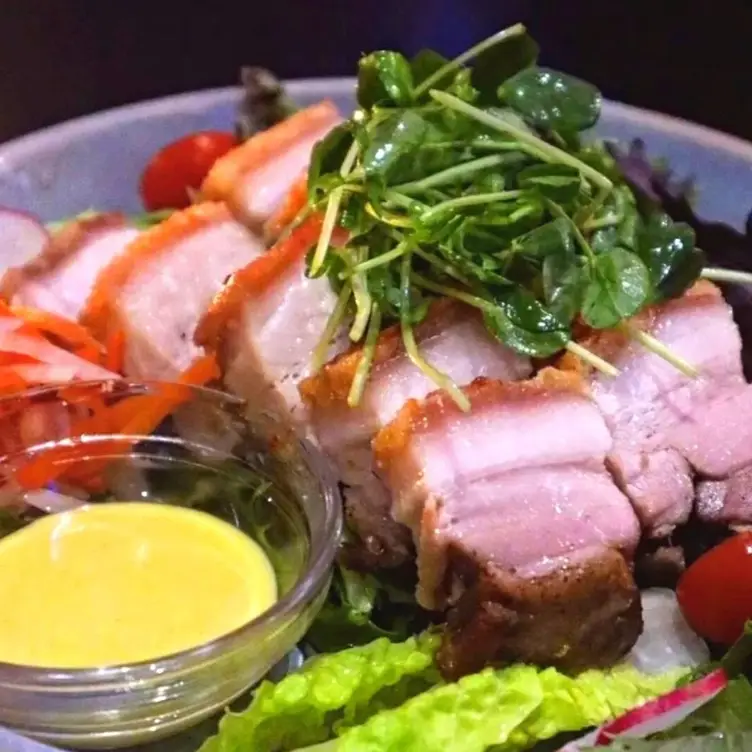 A plate of pork with salad and a dressing at Mr Wabi, one of the best Asian restaurants in Brisbane.