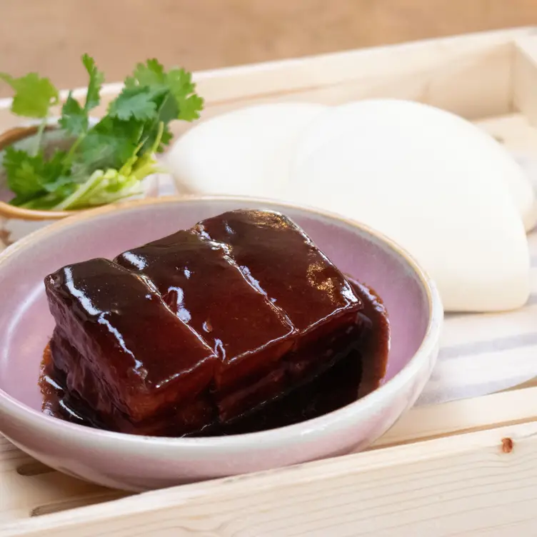 A bowl of glazed meat accompanied by salad and bao at Tai Tai, one of the best Asian restaurants in Brisbane.