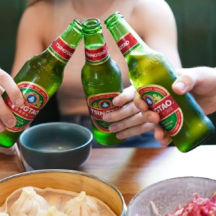 Guests clink bottles of beer at Uncle Wang, one of the best Asian restaurants in Brisbane.