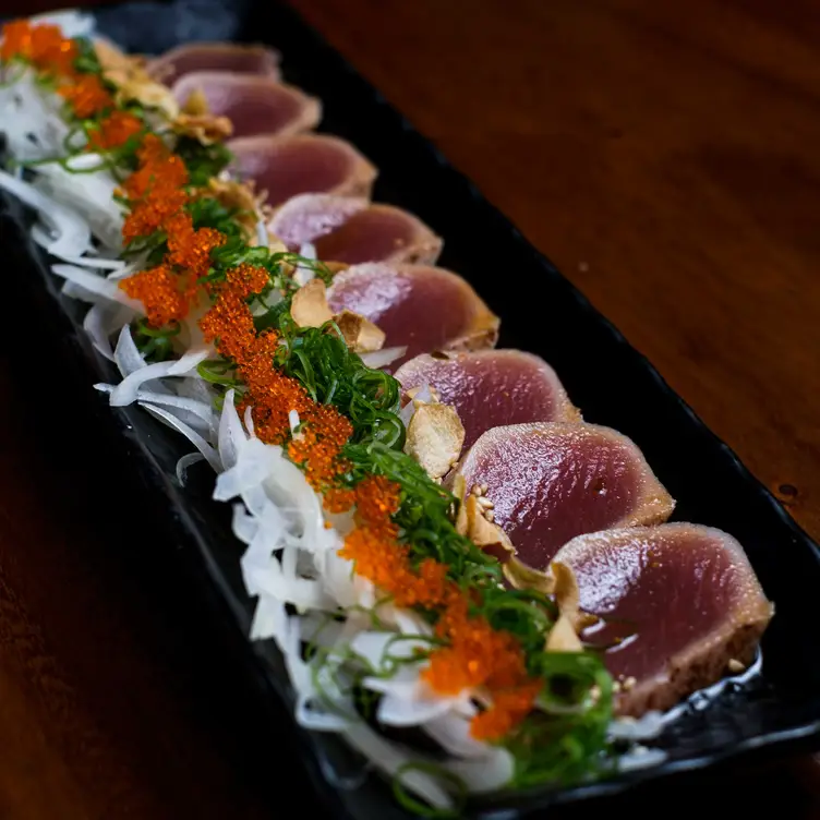 Close-up of a long plate of sashimi with garnishes at Hikari restaurant.