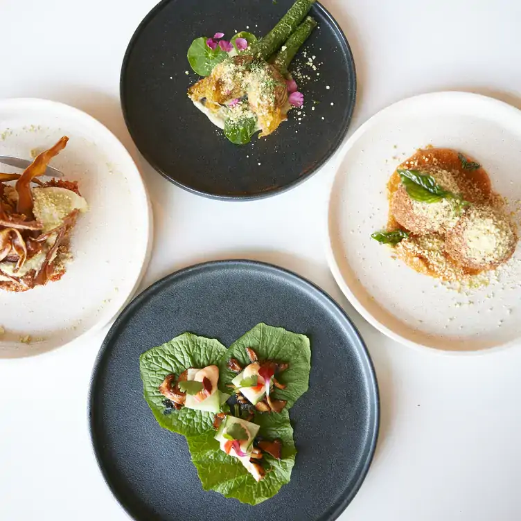 Four dishes garnished with petals and leaves served at Greenhouse Canteen and Bar, one of the best vegan restaurants on the Gold Coast.