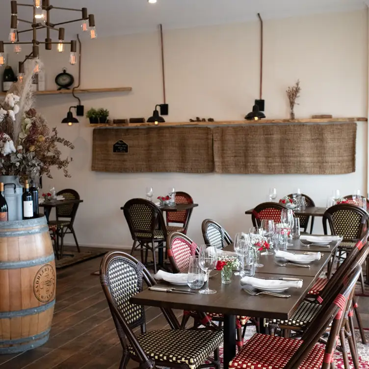 The interior of La Boucherie, showing the tables, chairs and a wine barrel topped with bottles and flowers in a bucket.