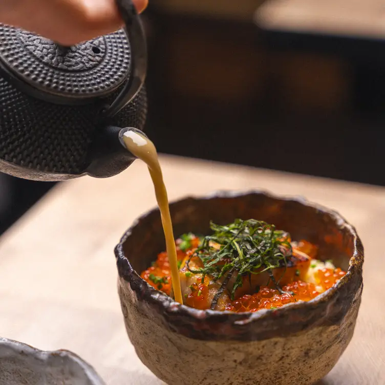 A teapot being poured and a dish topped with fish eggs at Tento.