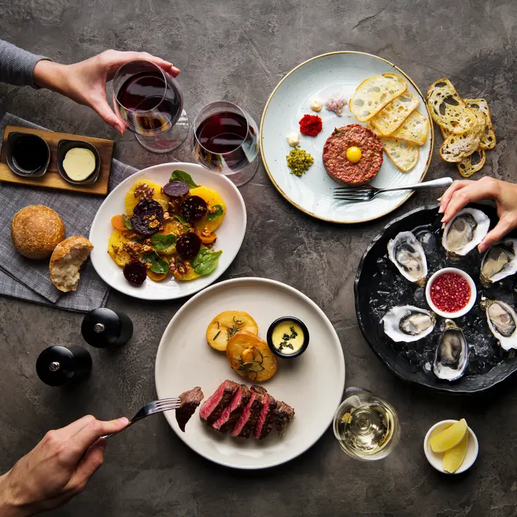 A few diners grab wine glasses, mussels and slices of steak at Black Hide by Gambaro at Treasury Brisbane.