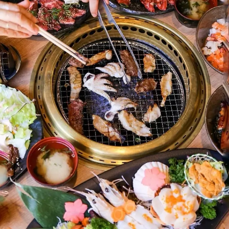 Diners cook small cuts of meat and seafood over the grill at the table at Touka Japanese Yakiniku Restaurant and Bar, one of the best Japanese restaurants in Sydney.