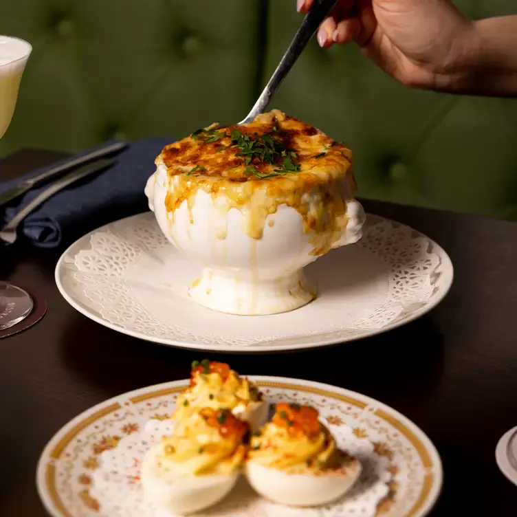 A diner digs into a cheesy dish served alongside devilled eggs at Bistro Francais, one of the best romantic restaurants in Adelaide.