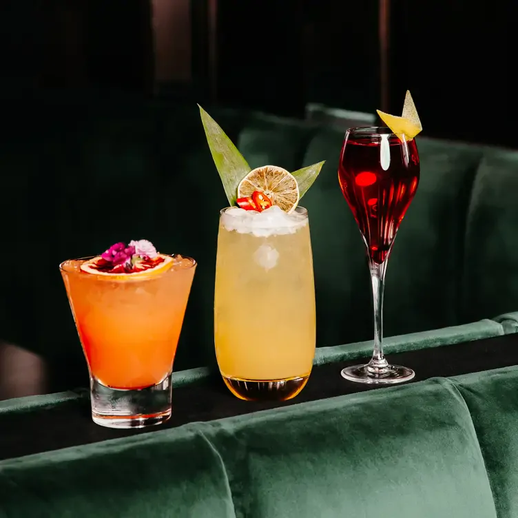 A selection of cocktails lined up on the back of a plush seat at Mr. Mista.