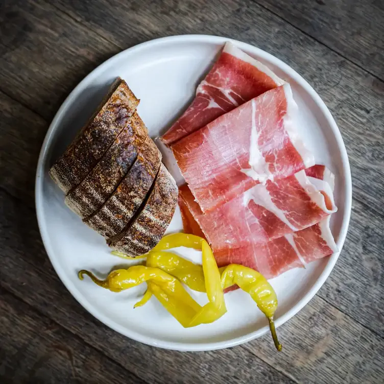 A plate with sliced bread, cured meat and chillis served at Udaberri Pintxos Y Vino, one of the best date night restaurants in Adelaide.