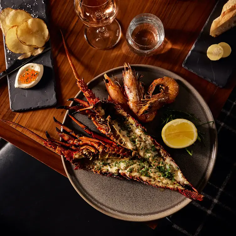 A seafood dish served alongside drinks and bread at Coal Cellar + Grill, one of the best romantic restaurants in Adelaide.