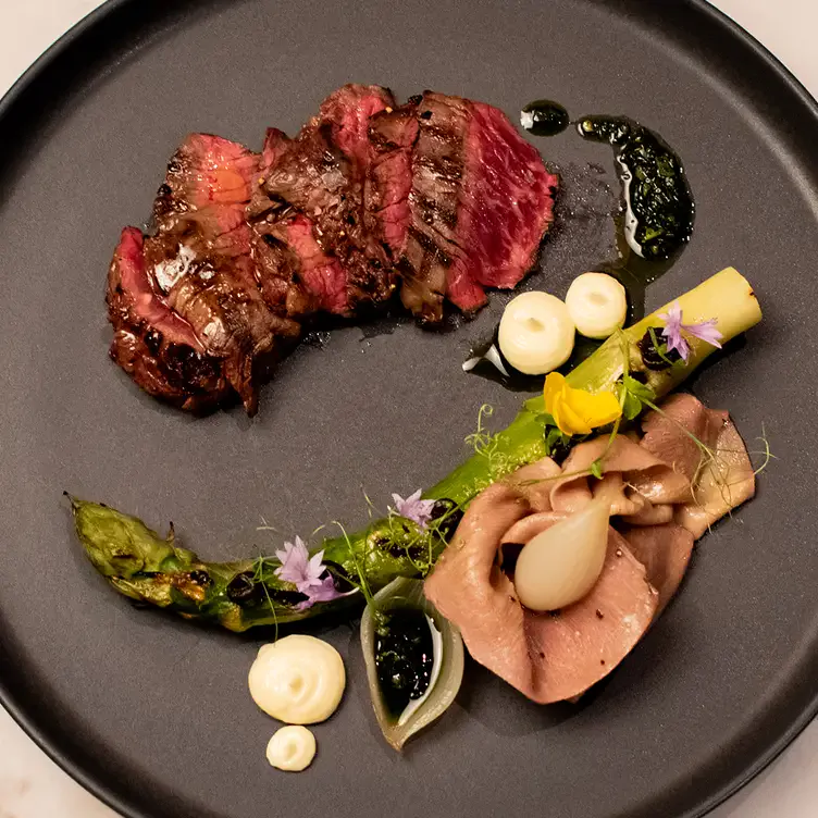 An entree of meat and asparagus with flower garnish served at Signature - Emporium Hotel South Bank.