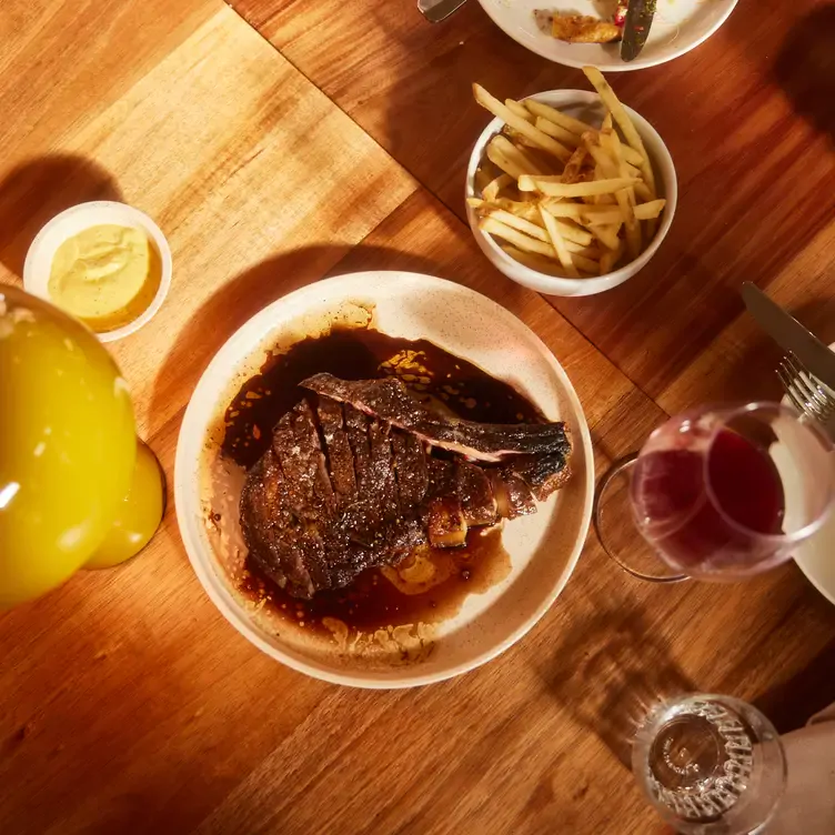 A sliced meat dish served alongside a bowl of chips, dip and a glass of wine at Longplay Bistro, one of the best romantic restaurants in Adelaide.