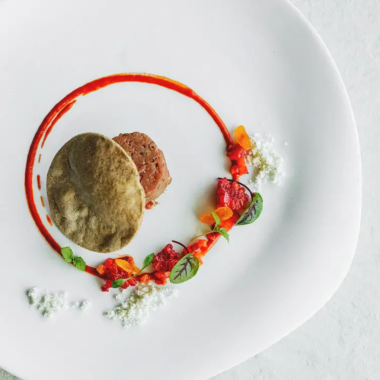 An entree of meat with a pancake, red sauce and garnish served at Deer Duck Bistro, one of the best date restaurants in Brisbane.