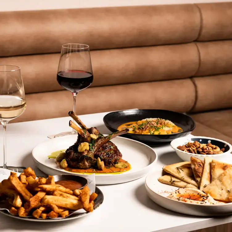 Several dishes served at Four Sides Bar and Kitchen, one of the best date night restaurants in Adelaide, including a plate of lamb and sides of chips and flatbread.